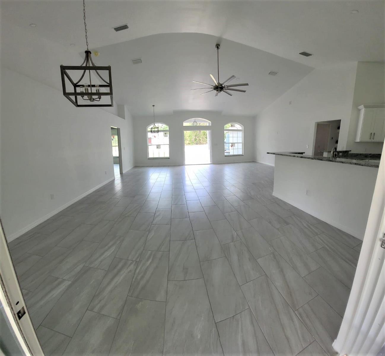 An open-concept living area features vaulted ceilings, gray tile flooring, and a kitchen breakfast bar — 14429 36th Avenue, FL 34491, FL