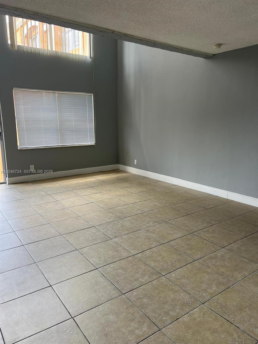 A living room features high ceilings, gray walls, and light-colored square floor tiles — 18051 NW 68th Ave # 204, Hialeah FL 33015, HIALEAH, FL