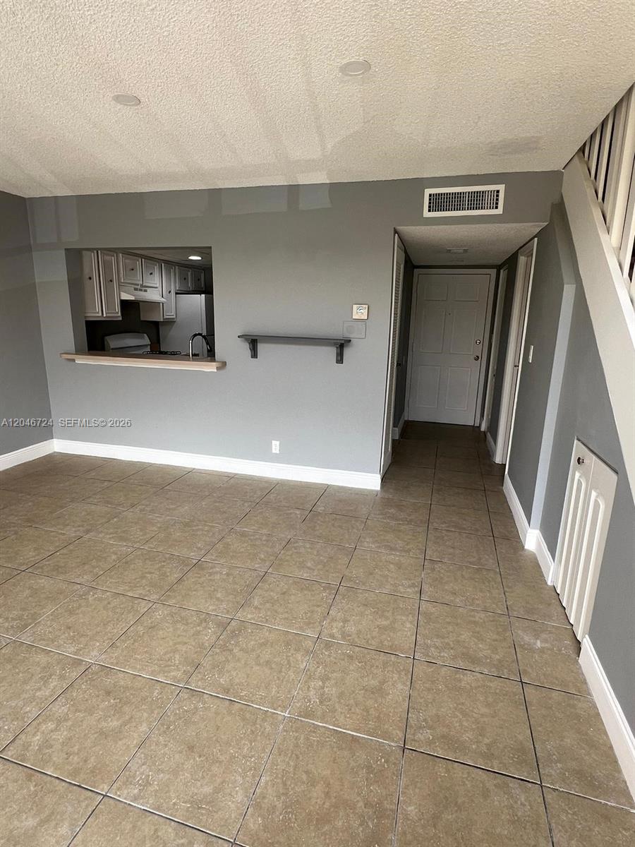 A living area features tile flooring, a kitchen pass-through window, and a staircase — 18051 NW 68th Ave # 204, Hialeah FL 33015, HIALEAH, FL