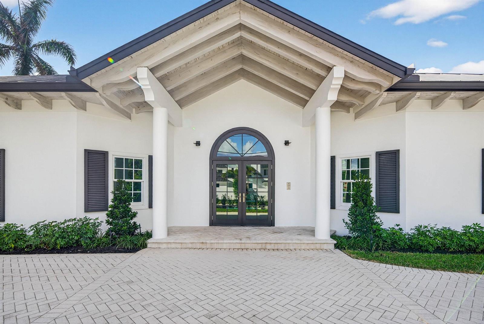 The exterior of a white house features a gabled entryway with two columns and shutters — 720 N Ocean Boulevard, Delray Beach FL 33483, DELRAY BEACH, FL