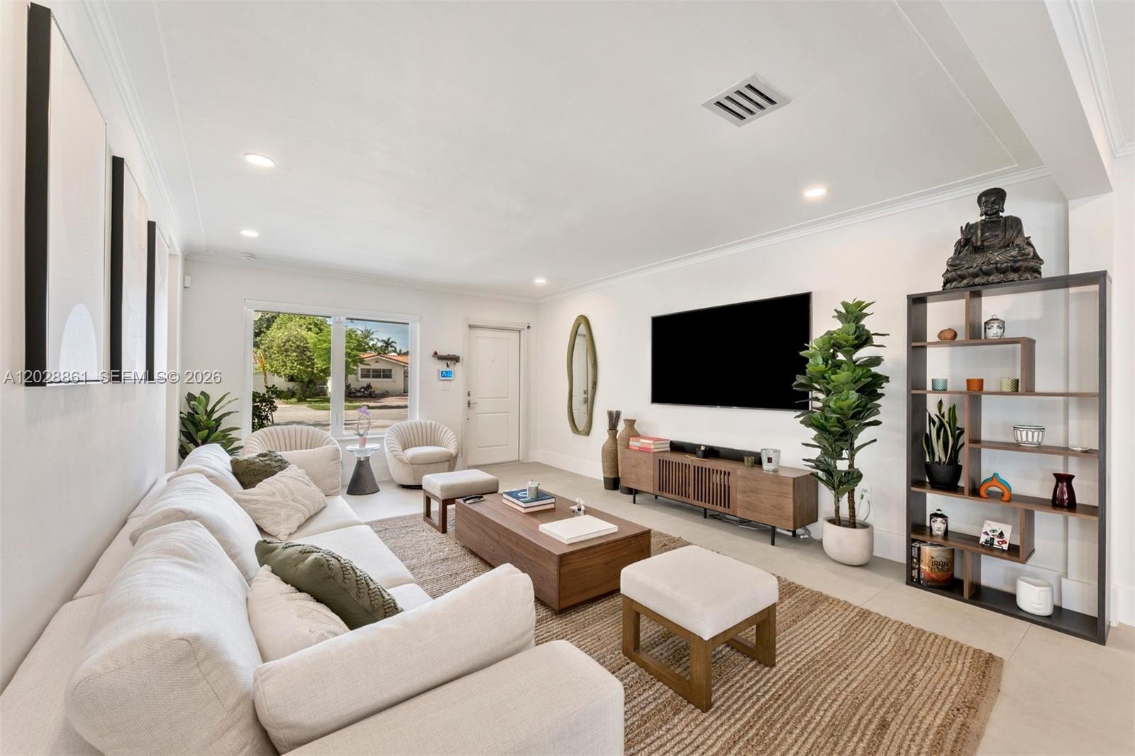 A bright living room features a white sofa, wooden coffee table, and a wall-mounted television — 45 Palermo Ave, Coral Gables FL 33134, CORAL GABLES, FL