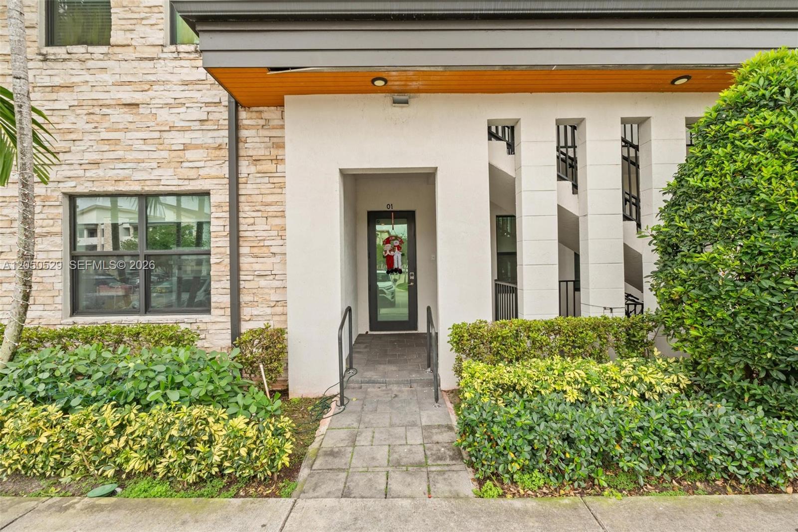 The exterior of a building features a stone facade, a glass front door, and landscaping — 7809 NW 104th Ave # 1, Doral FL 33178, DORAL, FL