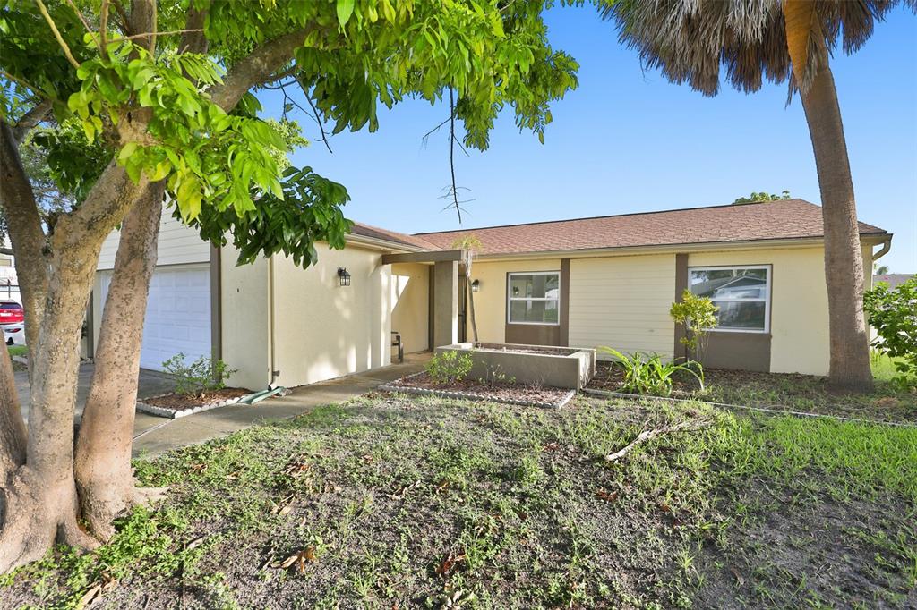 A single-story house with a light yellow exterior, a garage, and a front yard — 8433 SOMERSET DRIVE, LARGO, FL
