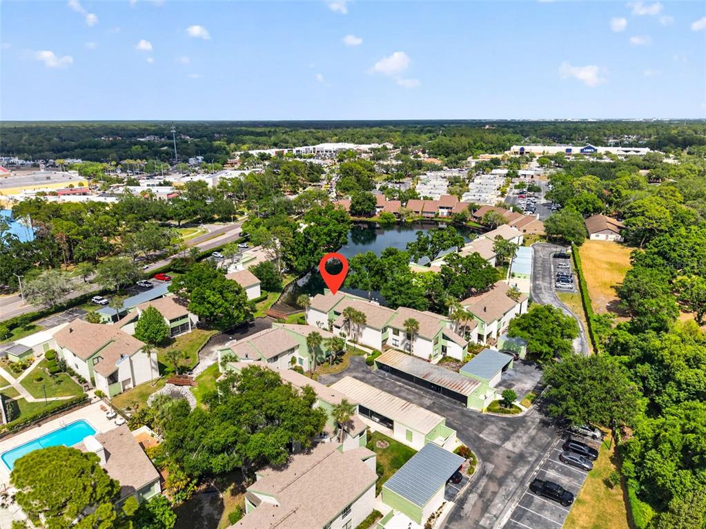 An aerial view shows a multi-unit apartment complex with a central pond and parking — 13405 PINE LAKE WAY UNIT 203, TAMPA, FL