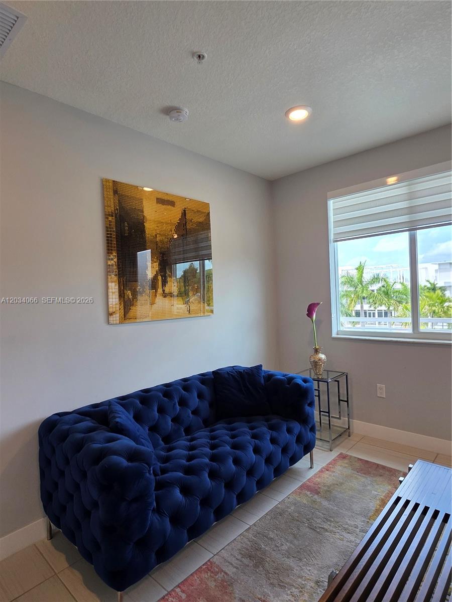 A blue tufted sofa sits in a room with a gold wall art piece — 10222 NW 64th Way # 302, Doral FL 33178, DORAL, FL