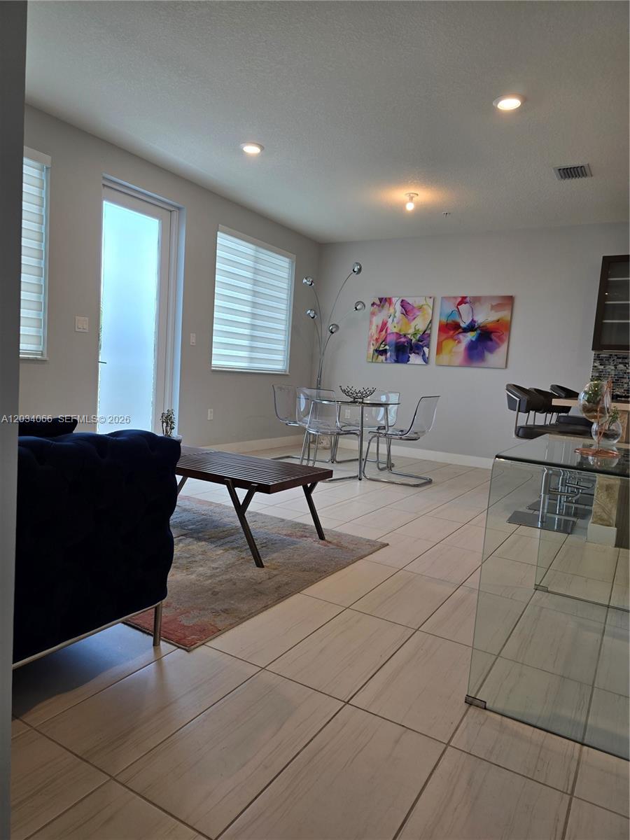 This open-concept living and dining area features tile flooring, modern furniture, and large windows — 10222 NW 64th Way # 302, Doral FL 33178, DORAL, FL