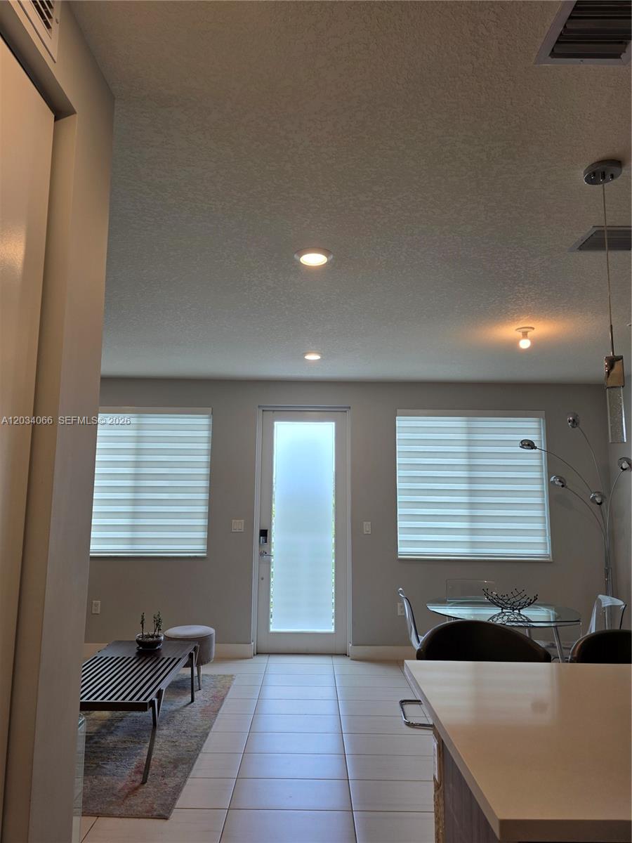 A bright living and dining area features tile floors, recessed lighting, and a glass-paneled door — 10222 NW 64th Way # 302, Doral FL 33178, DORAL, FL