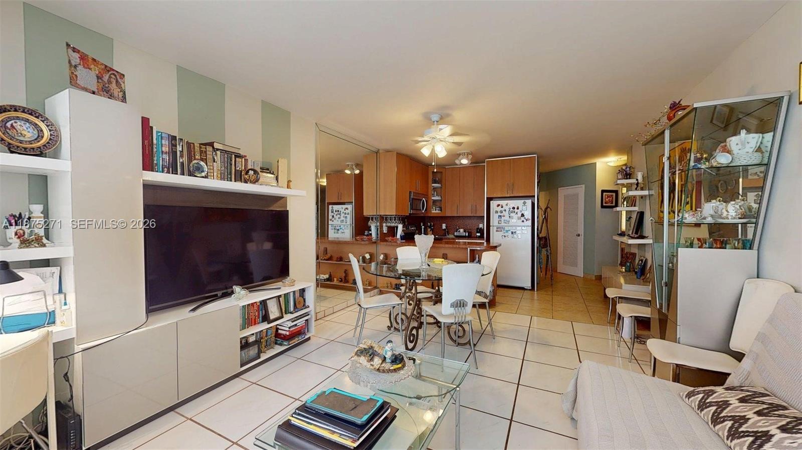 This living and dining area features white tile floors, a media console, and kitchen cabinetry — 1936 S Ocean Dr # 11D, Hallandale Beach FL 33009, HALLANDALE BEACH, FL