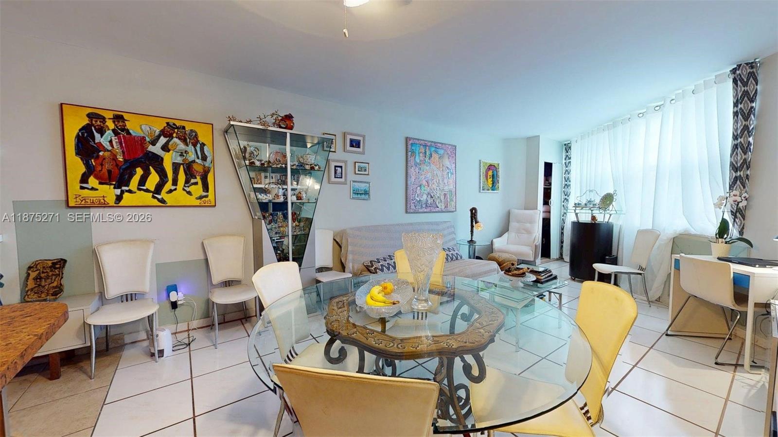 A dining and living area features a glass table, tiled floors, and various wall art — 1936 S Ocean Dr # 11D, Hallandale Beach FL 33009, HALLANDALE BEACH, FL