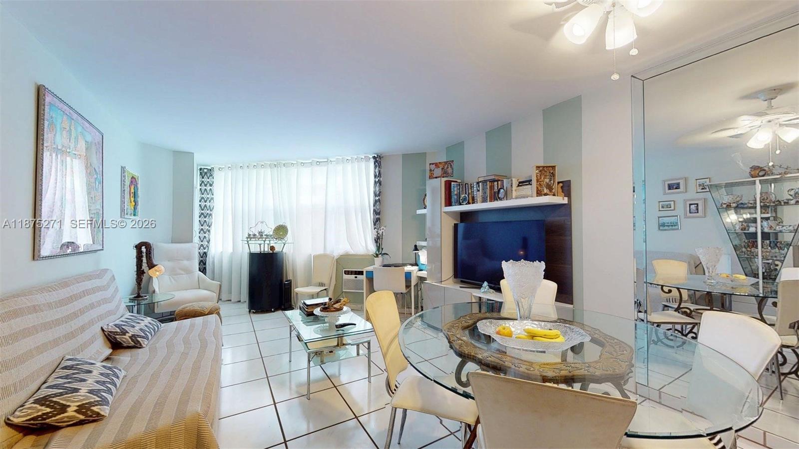 A living and dining area features white tile floors, a glass table, and a television — 1936 S Ocean Dr # 11D, Hallandale Beach FL 33009, HALLANDALE BEACH, FL