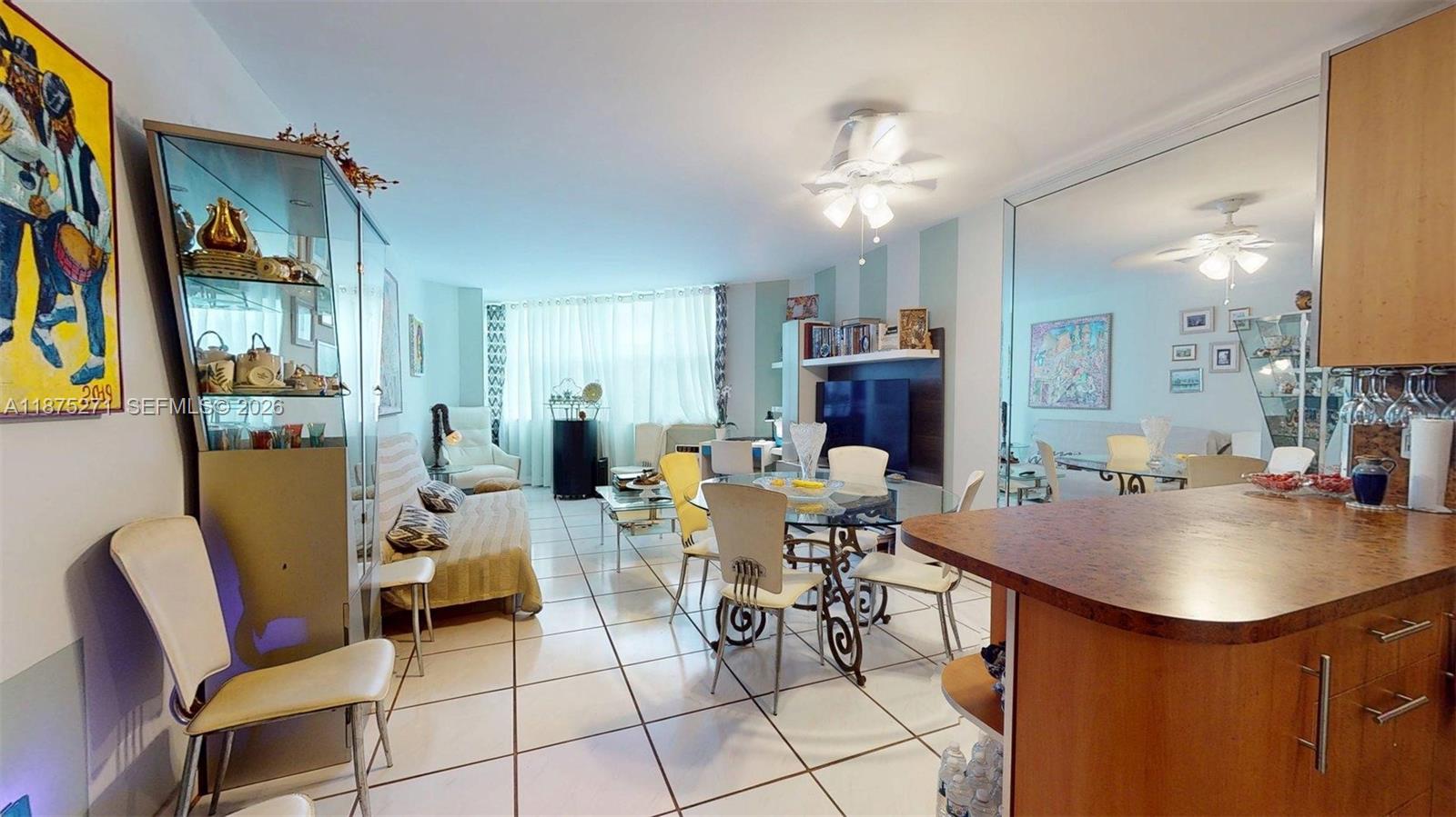 A dining and living area features tile floors, a glass table, and a mirrored wall — 1936 S Ocean Dr # 11D, Hallandale Beach FL 33009, HALLANDALE BEACH, FL