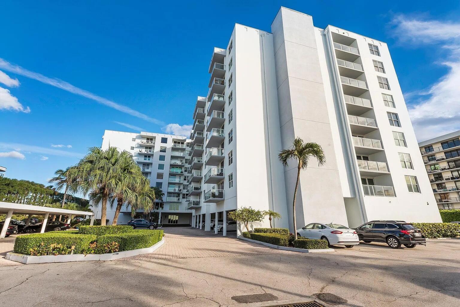 A multi-story white apartment building with balconies stands above a paved parking lot — 3450 S Ocean Boulevard # 6150, Palm Beach FL 33480, PALM BEACH, FL
