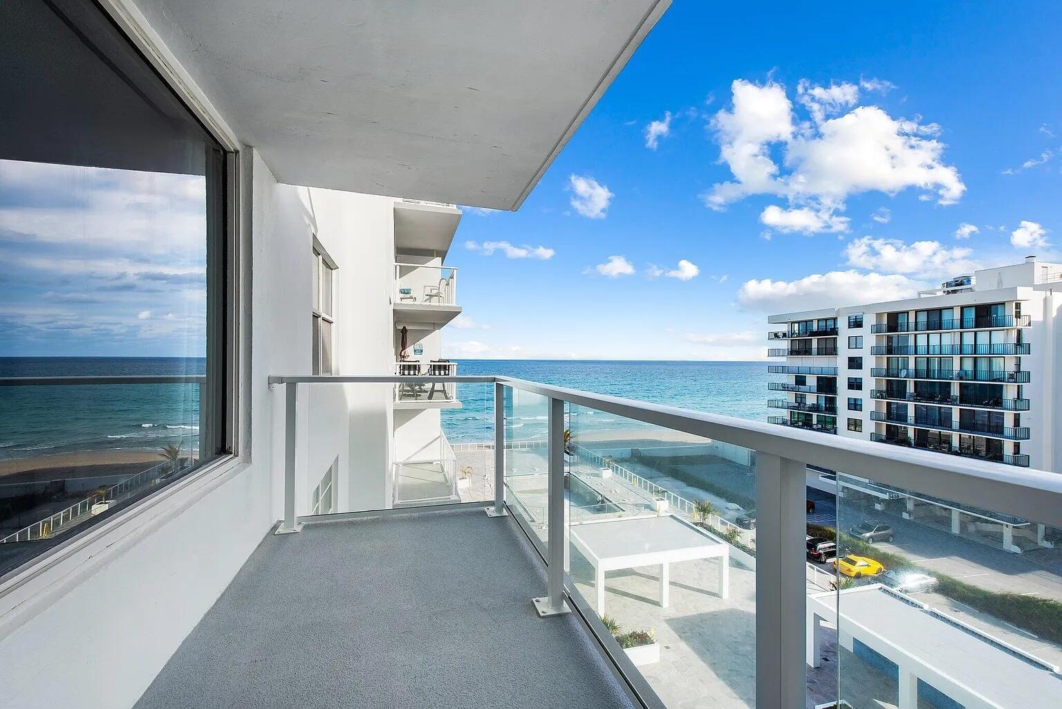 A balcony with a glass railing overlooks the ocean and a neighboring building — 3450 S Ocean Boulevard # 6150, Palm Beach FL 33480, PALM BEACH, FL