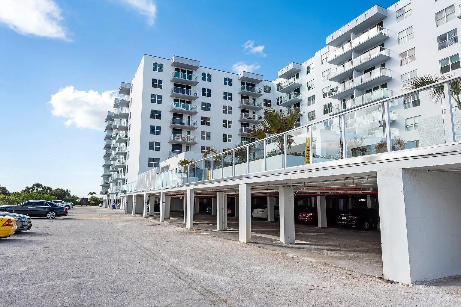 A multi-story white apartment building with a covered ground-level parking area and outdoor parking — 3450 S Ocean Boulevard # 6150, Palm Beach FL 33480, PALM BEACH, FL