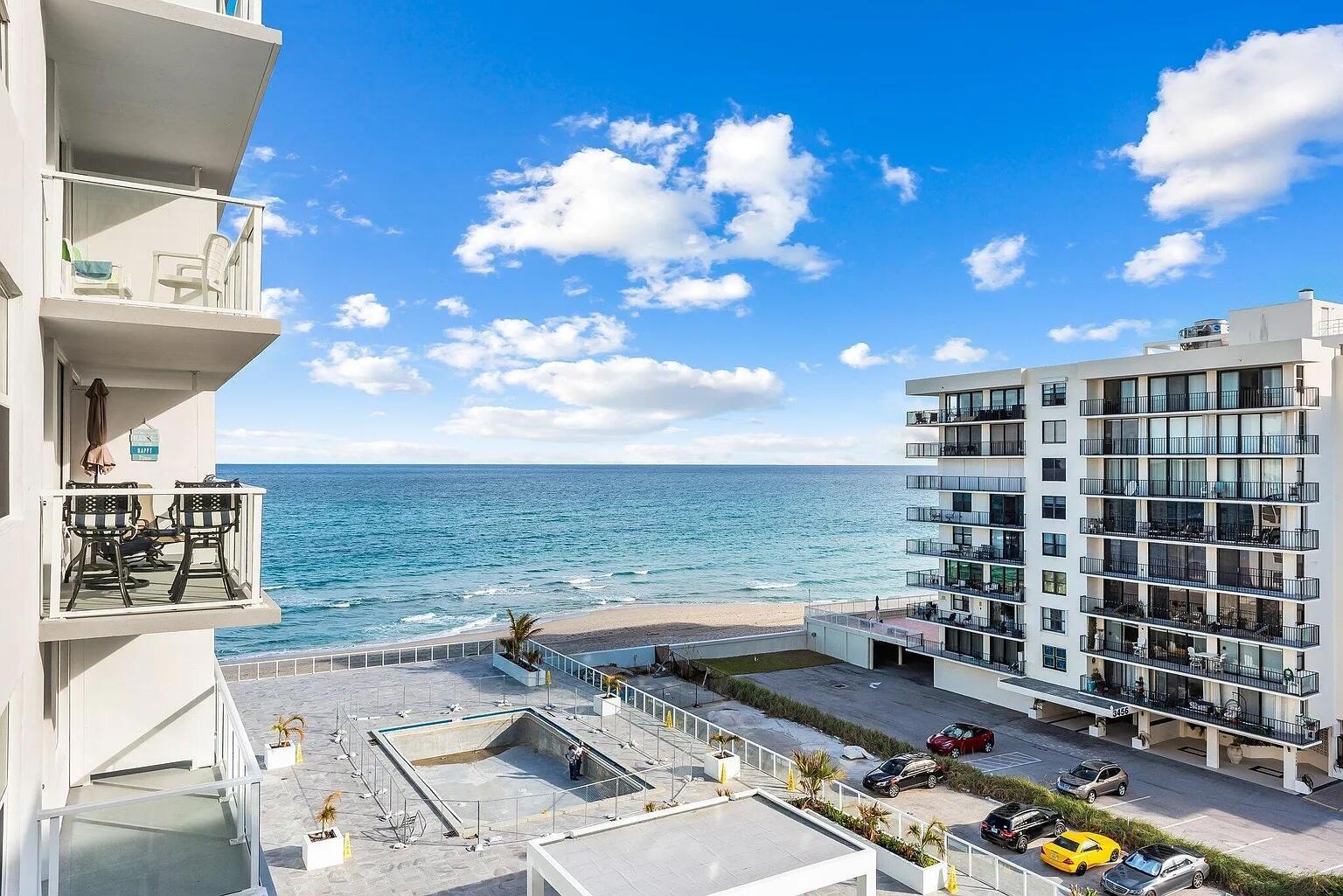 An elevated view of a beachside apartment complex featuring balconies, a pool, and parking lot — 3450 S Ocean Boulevard # 6150, Palm Beach FL 33480, PALM BEACH, FL