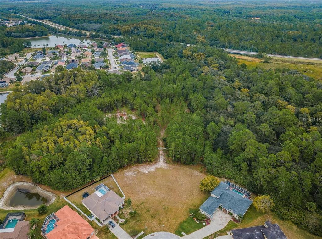 An aerial view shows a residential lot cleared for construction surrounded by dense forest — 0 SHOOTING STAR COURT, NEW PORT RICHEY, FL