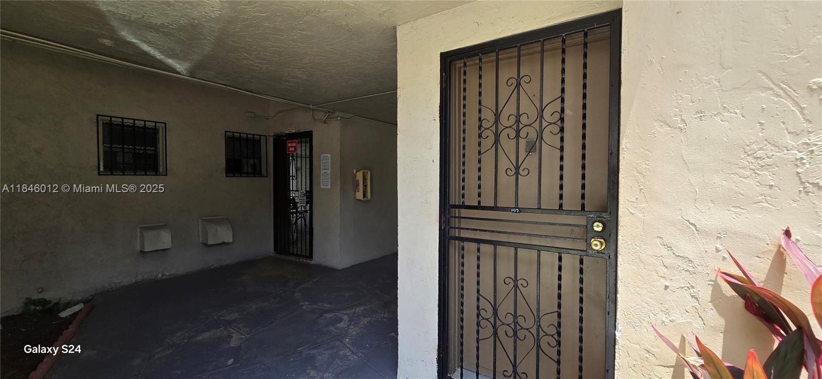 An exterior view shows a building entrance with a metal security door and walkway — 816 NW 87th Ave # 107, Miami FL 33172, MIAMI, FL