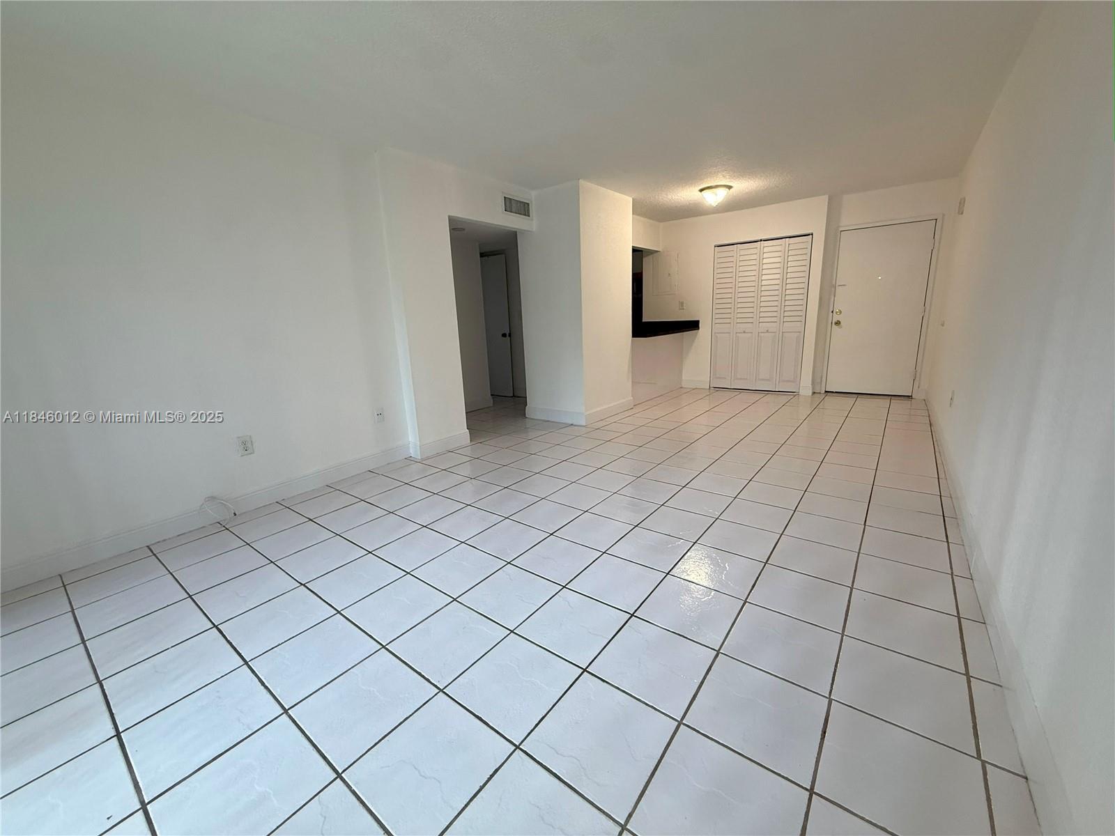 An empty room features white tiled floors, white walls, a closet, and an entryway — 816 NW 87th Ave # 107, Miami FL 33172, MIAMI, FL