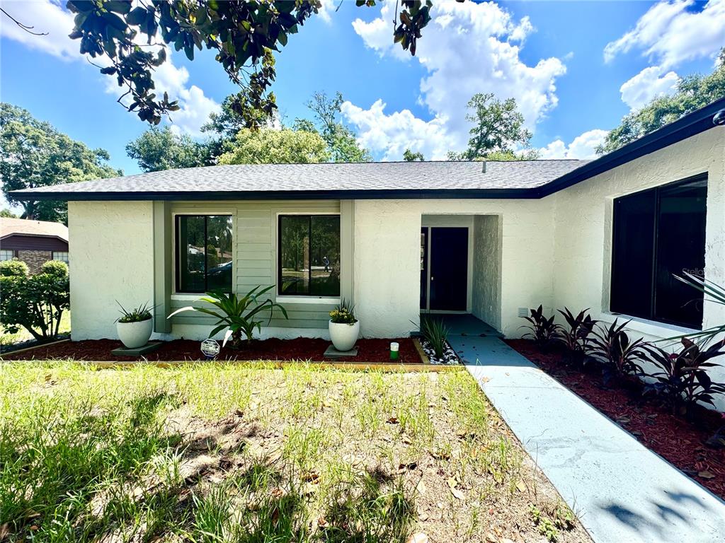 A white, single-story house with a gray roof, dark-framed windows, and a concrete walkway — 5509 LIGHTHOUSE ROAD, ORLANDO, FL