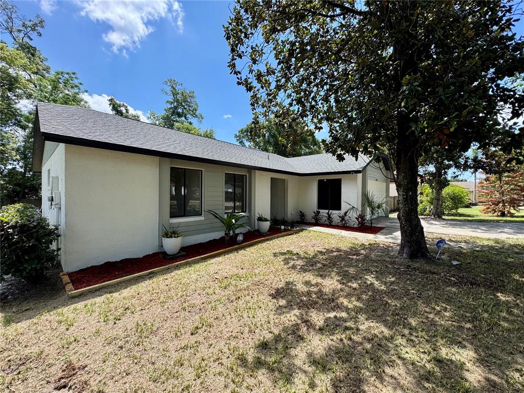A single-story house with a white stucco exterior, dark roof, and a large front tree — 5509 LIGHTHOUSE ROAD, ORLANDO, FL