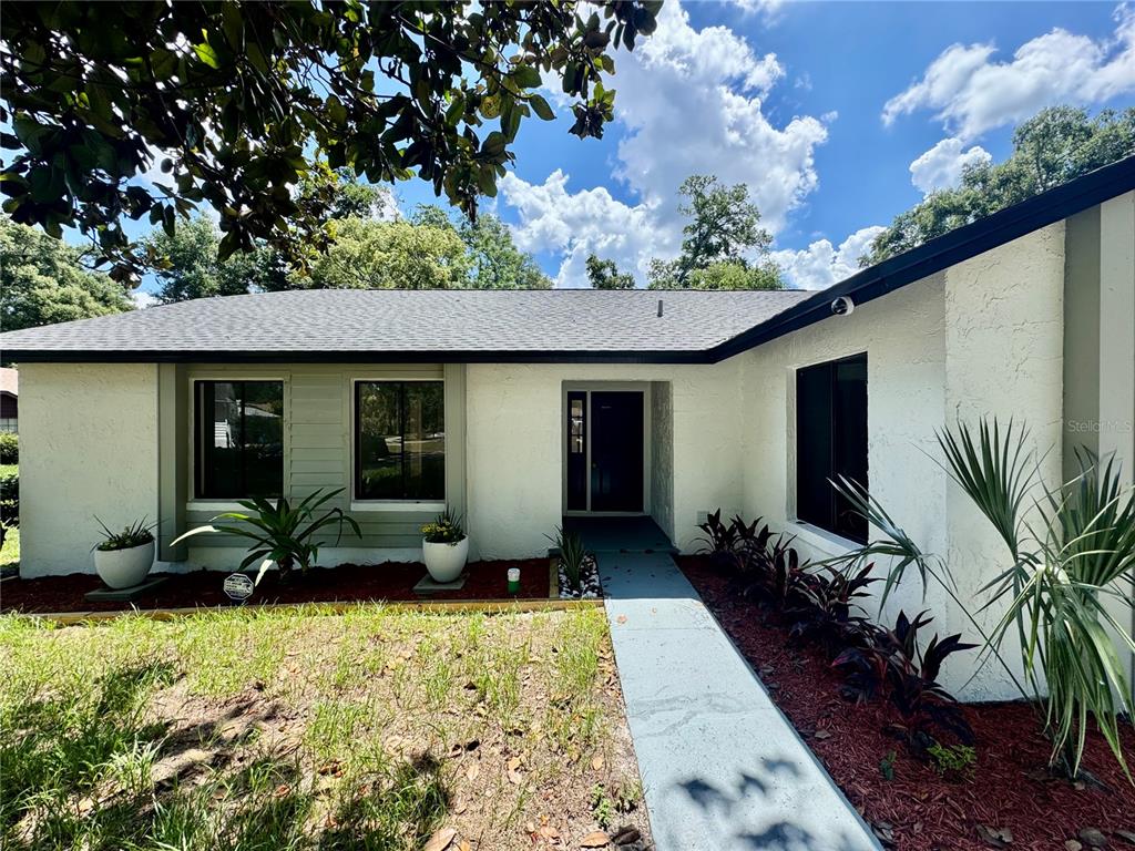 A single-story white house with a dark roof, a front walkway, and landscaped garden beds — 5509 LIGHTHOUSE ROAD, ORLANDO, FL