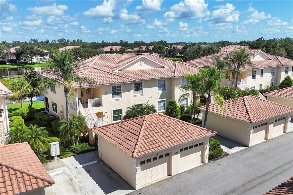 An exterior view of a two-story apartment building with a white staircase and palm trees — 4206 VICENZA DRIVE UNIT C24, VENICE, FL