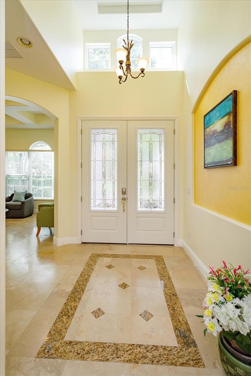 A bright foyer features a double front door, tile flooring with an inlay, and chandelier — 8920 VIA BELLA NOTTE, ORLANDO, FL