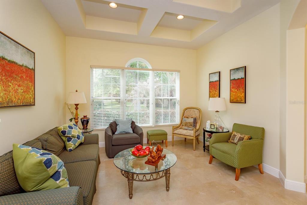 A living room features a tray ceiling, tile flooring, a glass coffee table, and seating — 8920 VIA BELLA NOTTE, ORLANDO, FL