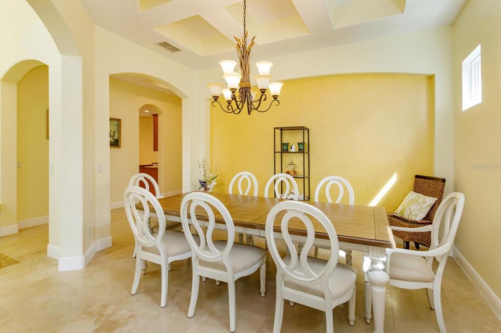 A dining room features a wooden table, white chairs, a chandelier, and yellow accent walls — 8920 VIA BELLA NOTTE, ORLANDO, FL
