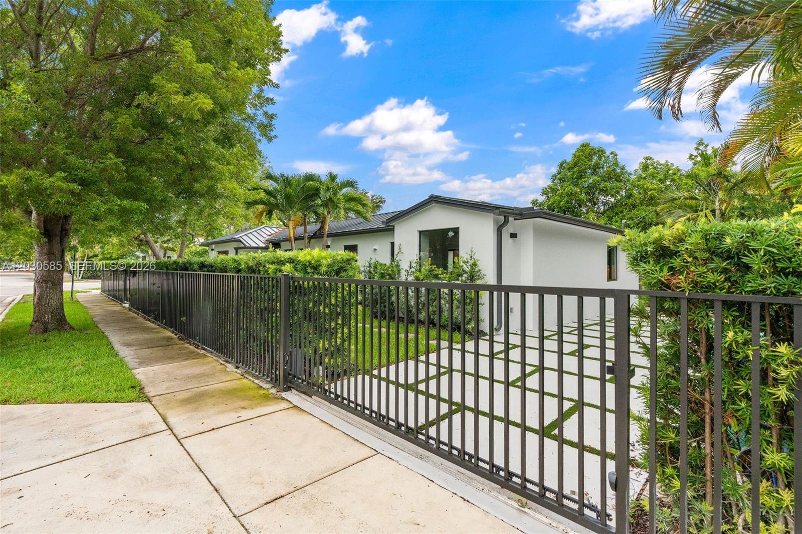 A white house with a metal roof is viewed behind a black metal fence — 2286 SW 21st Ave, Miami FL 33145, MIAMI, FL