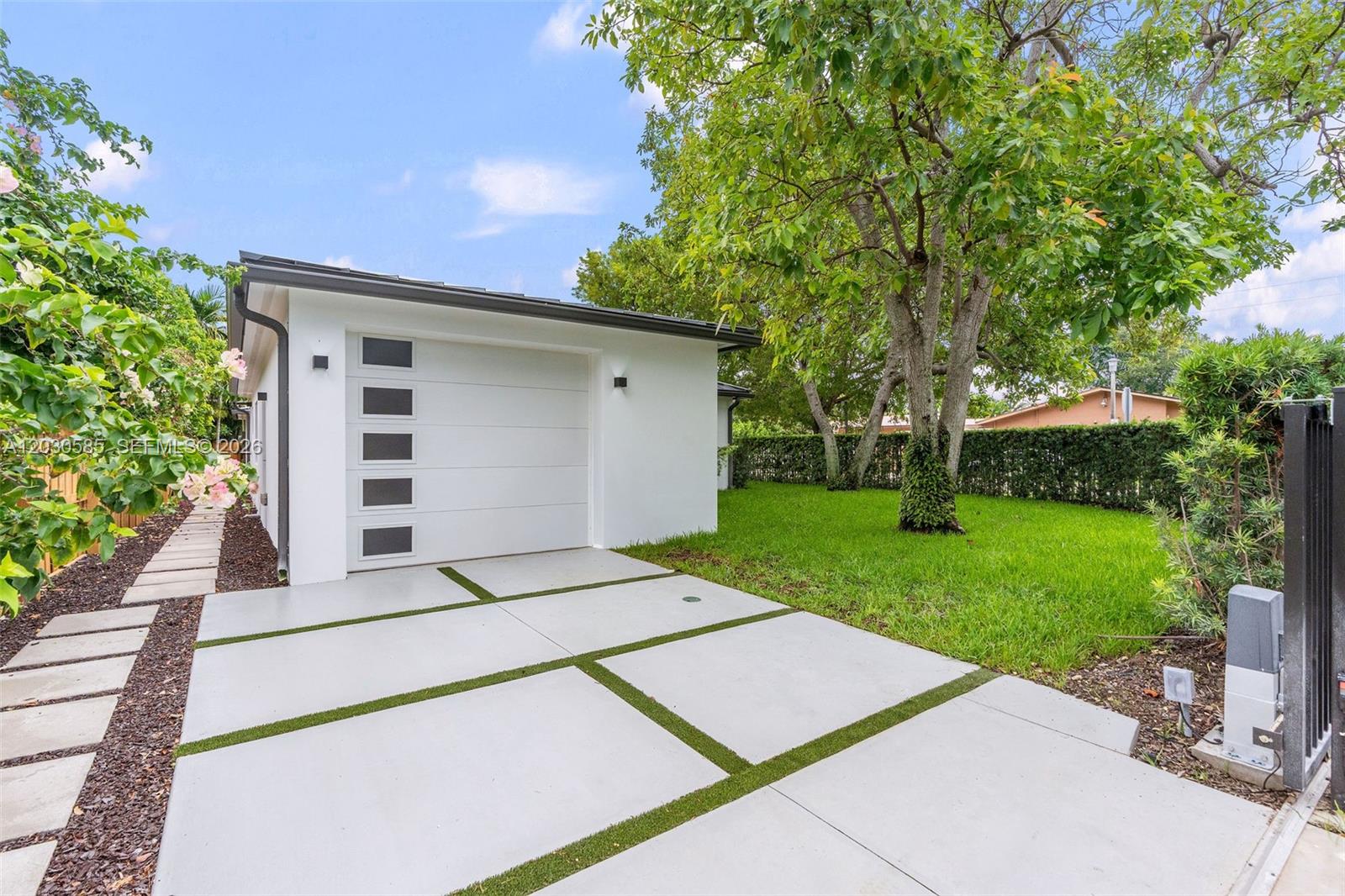 A modern white garage with a glass-paneled door sits beside a concrete driveway with grass — 2286 SW 21st Ave, Miami FL 33145, MIAMI, FL