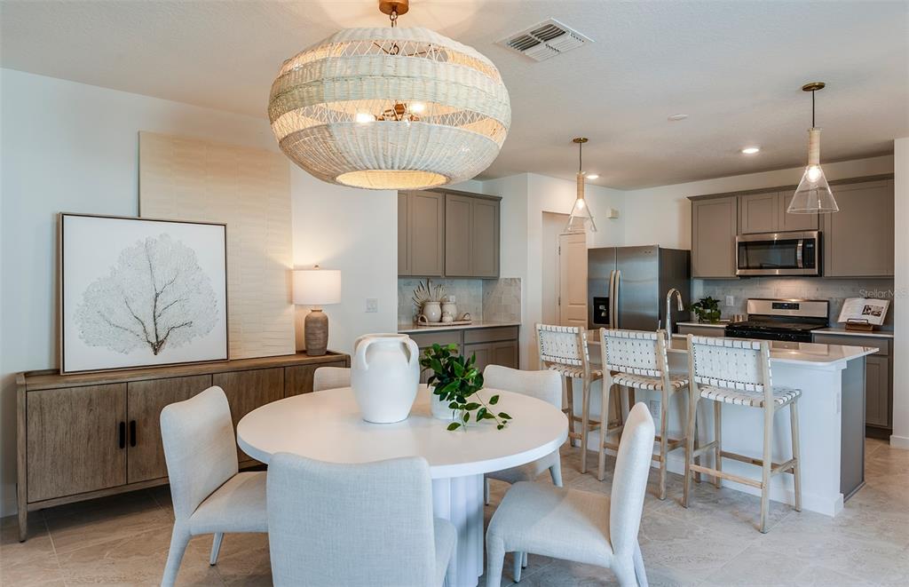 A dining area with a round table and chairs sits adjacent to a modern kitchen — 36798 KISTNA DRIVE, ZEPHYRHILLS, FL