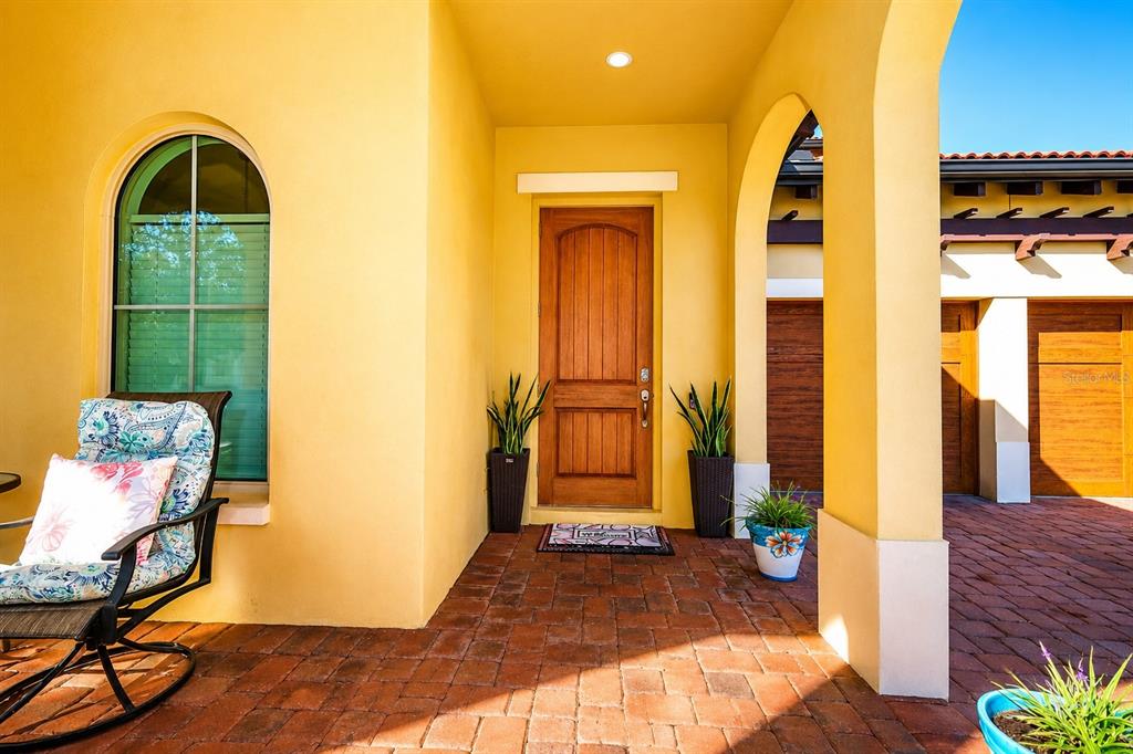 A covered front porch with a wooden door, arched window, and brick paver flooring — 15149 CANOE PLACE, WINTER GARDEN, FL