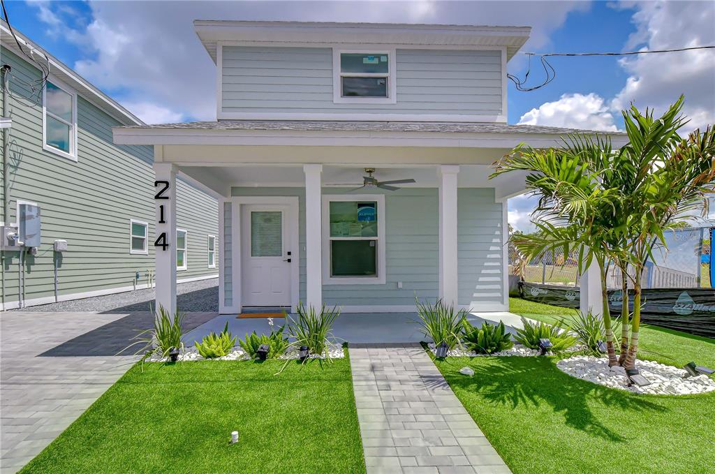 A light blue two-story house features a front porch, a walkway, and artificial turf — 214 8TH AVENUE DRIVE W, BRADENTON, FL
