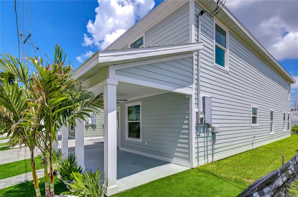 A light blue house with a covered porch, white trim, and a green lawn — 214 8TH AVENUE DRIVE W, BRADENTON, FL