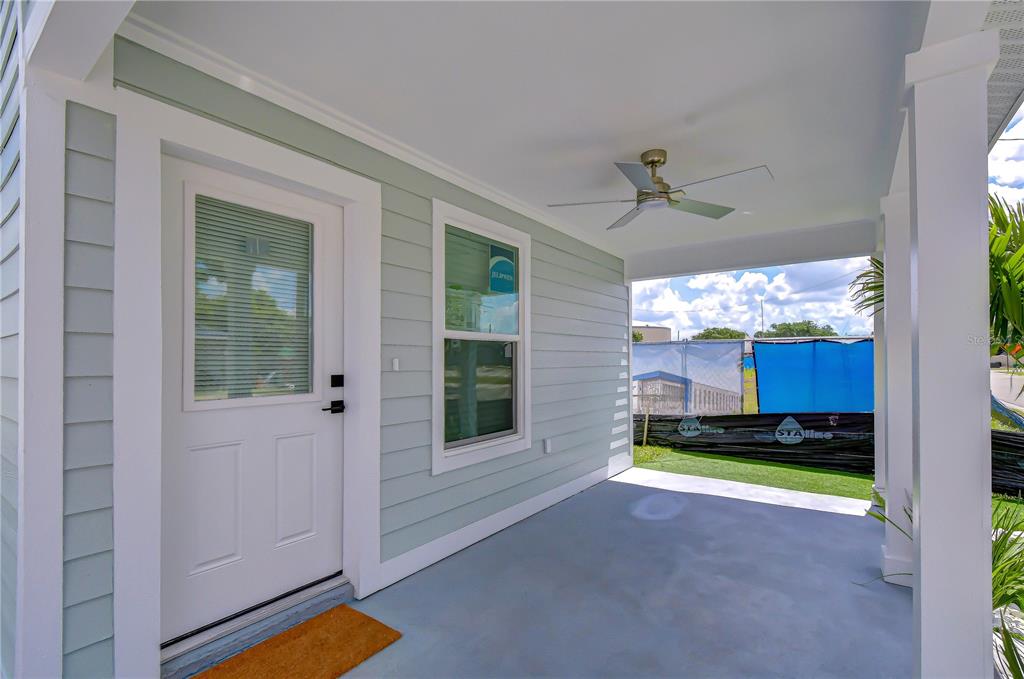A covered porch with light green siding, a white door, and a ceiling fan — 214 8TH AVENUE DRIVE W, BRADENTON, FL