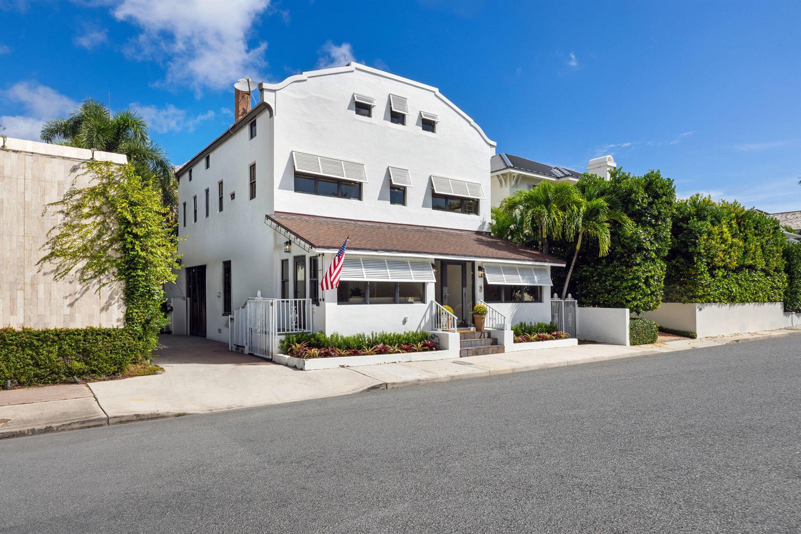 A white three-story house with a brown roof and American flag sits on a street — 269 Park Avenue, Palm Beach FL 33480, PALM BEACH, FL