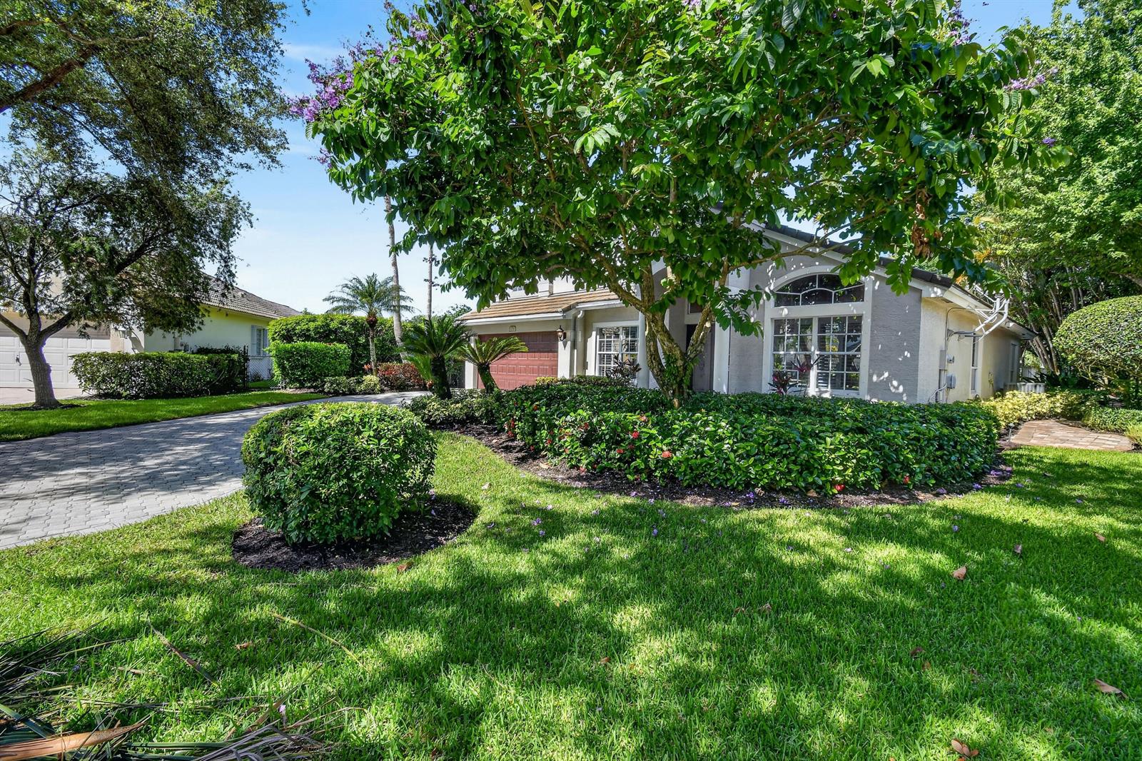 A single-story house with a paved driveway, manicured landscaping, and a large tree in front — 276 Swan Lane, Jupiter FL 33458, JUPITER, FL