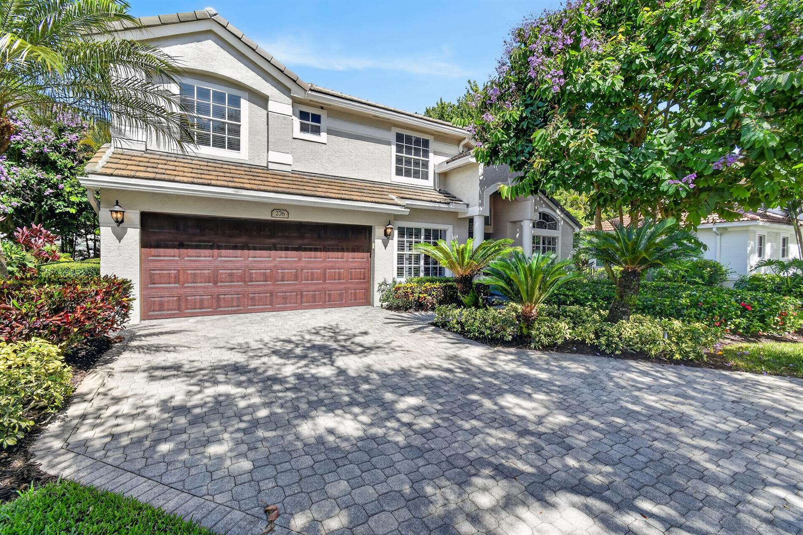 A two-story house with a brown garage door, paved driveway, and lush landscaping — 276 Swan Lane, Jupiter FL 33458, JUPITER, FL