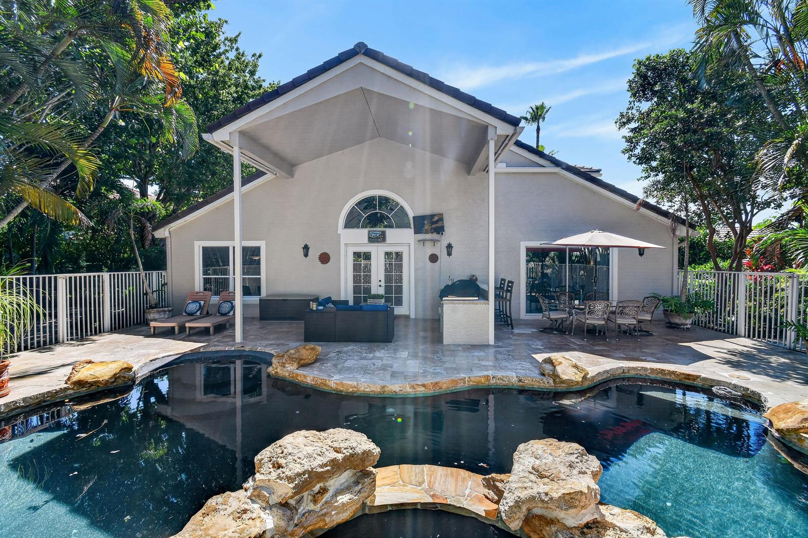 A backyard patio features a swimming pool, outdoor kitchen, and covered seating area — 276 Swan Lane, Jupiter FL 33458, JUPITER, FL