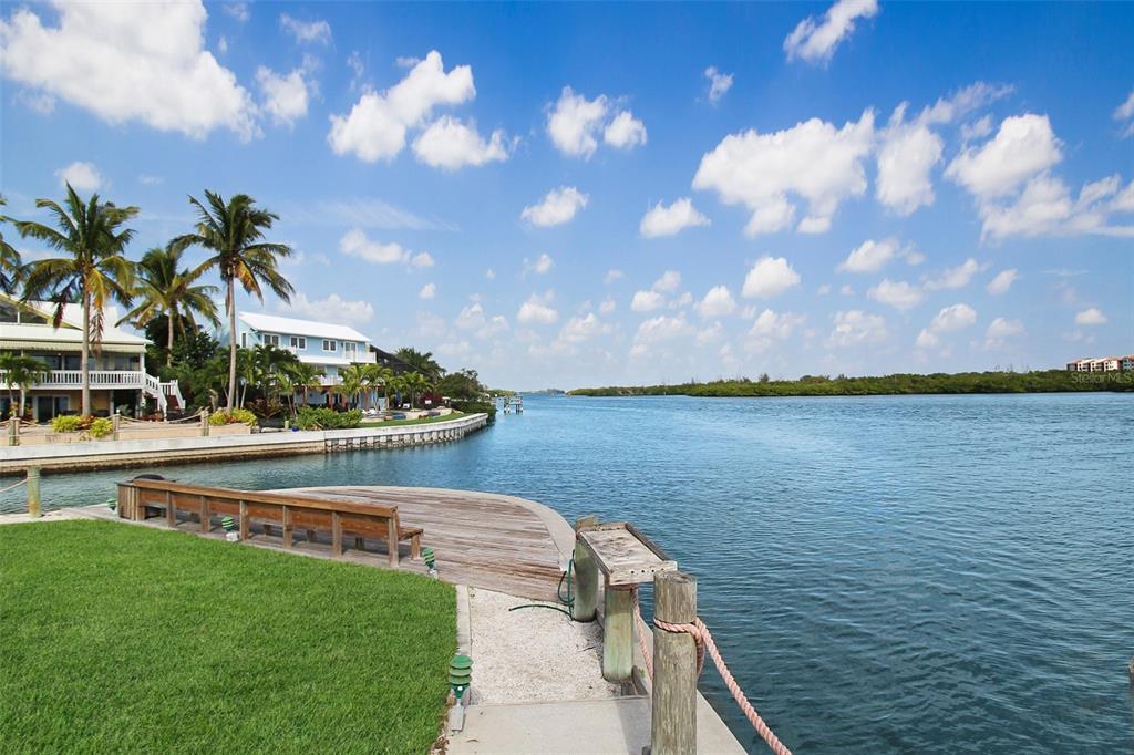 A wooden dock with a bench overlooks a canal lined with palm trees and houses — 1389 SIESTA BAYSIDE DRIVE UNIT 1389-F, SARASOTA, FL
