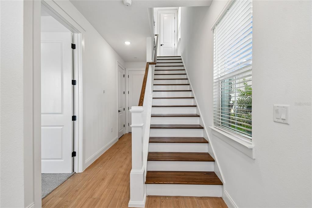 A staircase with dark wood treads and white risers leads to an upper landing — 230 PASQUALA WAY, OVIEDO, FL