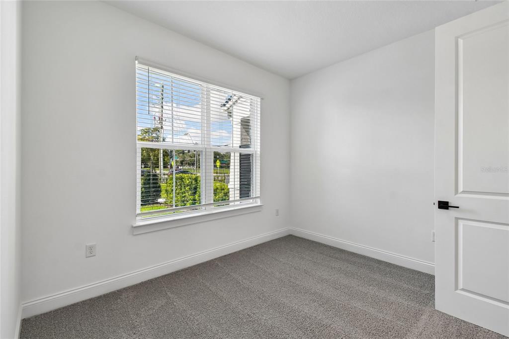 An empty bedroom features gray carpet, white walls, a single window, and a white door — 230 PASQUALA WAY, OVIEDO, FL