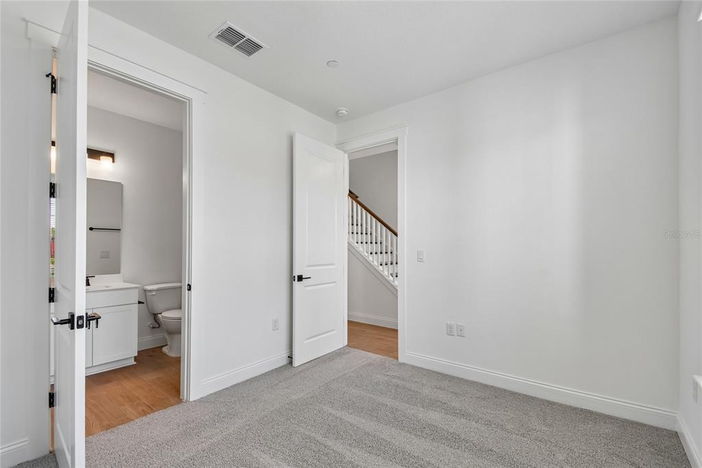 A carpeted bedroom features a white door leading to a bathroom and another to stairs — 230 PASQUALA WAY, OVIEDO, FL