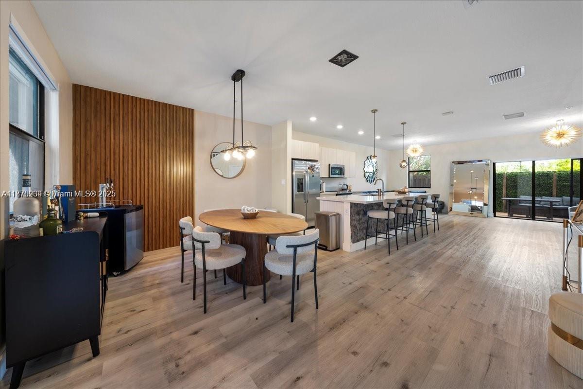 An open-concept kitchen and dining area features light wood flooring and a slatted wood wall — 10413 NW 82nd St # 9, Doral FL 33178, DORAL, FL