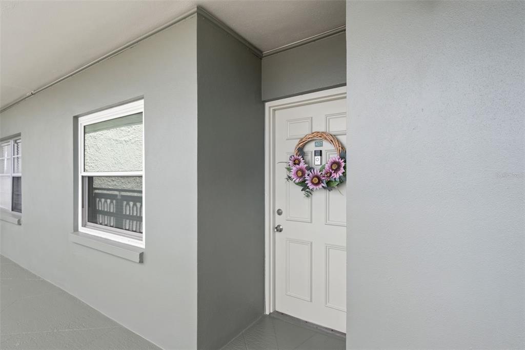 A white front door with a floral wreath and a window on a gray exterior wall — 7321 CENTRAL AVENUE UNIT 407, ST PETERSBURG, FL