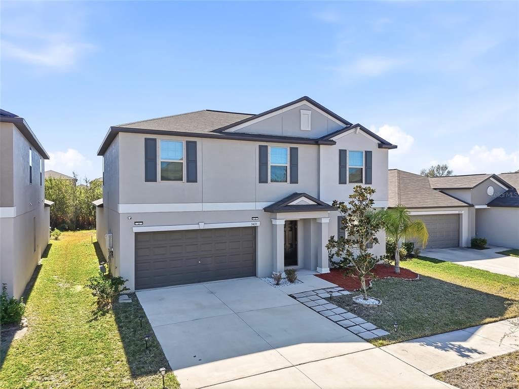A two-story suburban house features a gray stucco exterior, a two-car garage, and shutters — 5431 AMARYLLIS GARDEN STREET, RUSKIN, FL
