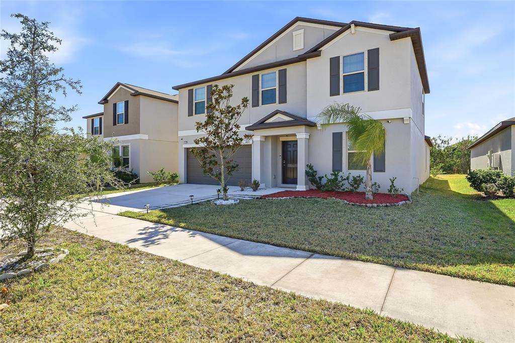 A two-story suburban house with a gray exterior, dark shutters, and a concrete driveway — 5431 AMARYLLIS GARDEN STREET, RUSKIN, FL
