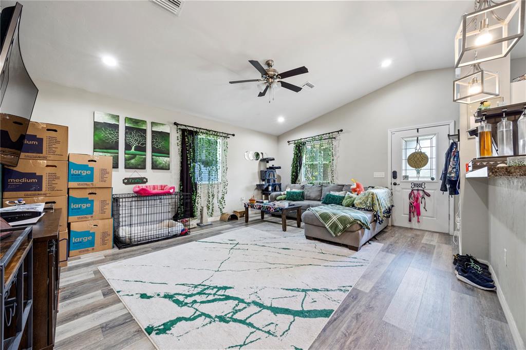 A living room features a gray sectional sofa, a dog crate, and a large area rug — 14208 NW 136TH TERRACE, ALACHUA, FL
