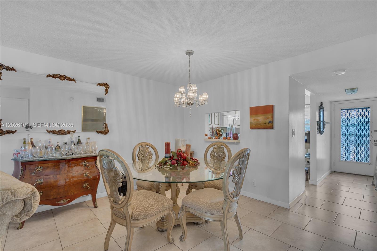 A dining room features a glass-topped table, ornate chairs, a chandelier, and a wooden sideboard — 3551 Inverrary Dr # 208, Lauderhill FL 33319, LAUDERHILL, FL